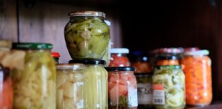 Smaki świata w twojej spiżarni: must have produkty klasy premium Kolorowe warzywa w słoikach na drewnianej półce w domowej spiżarni