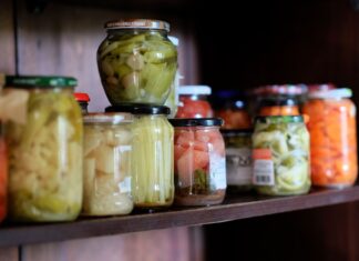 Smaki świata w twojej spiżarni: must have produkty klasy premium Kolorowe warzywa w słoikach na drewnianej półce w domowej spiżarni