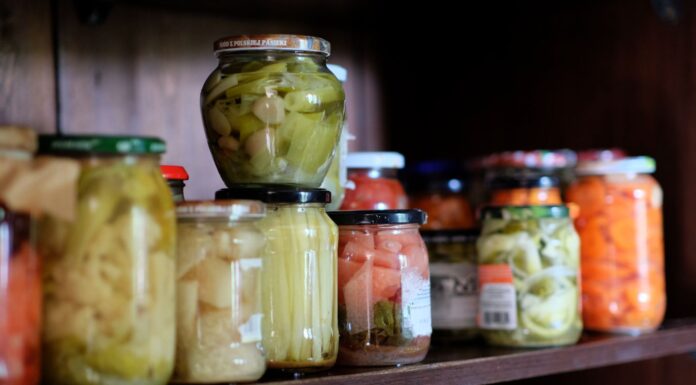 Smaki świata w twojej spiżarni: must have produkty klasy premium Kolorowe warzywa w słoikach na drewnianej półce w domowej spiżarni
