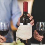 Para degustuje czerwone wino z butelki w ciemnym materiale