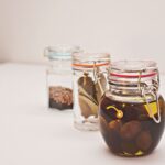 Słoiki z marynowanymi oliwkami i przyprawami na kuchennym blacie