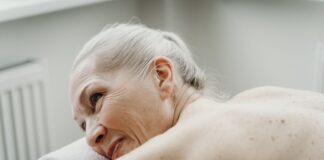 Jak stworzyć bezpieczną i komfortową strefę wellness dla klientów z nadciśnieniem i chorobami serca Starsza kobieta z siwymi włosami uśmiecha się podczas relaksu w spa