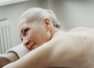Starsza kobieta z siwymi włosami uśmiecha się podczas relaksu w spa