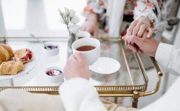 Eleganckie śniadanie we dwoje z herbatą, wypiekami i splecionymi dłońmi