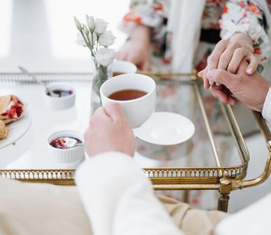 Eleganckie śniadanie we dwoje z herbatą, wypiekami i splecionymi dłońmi